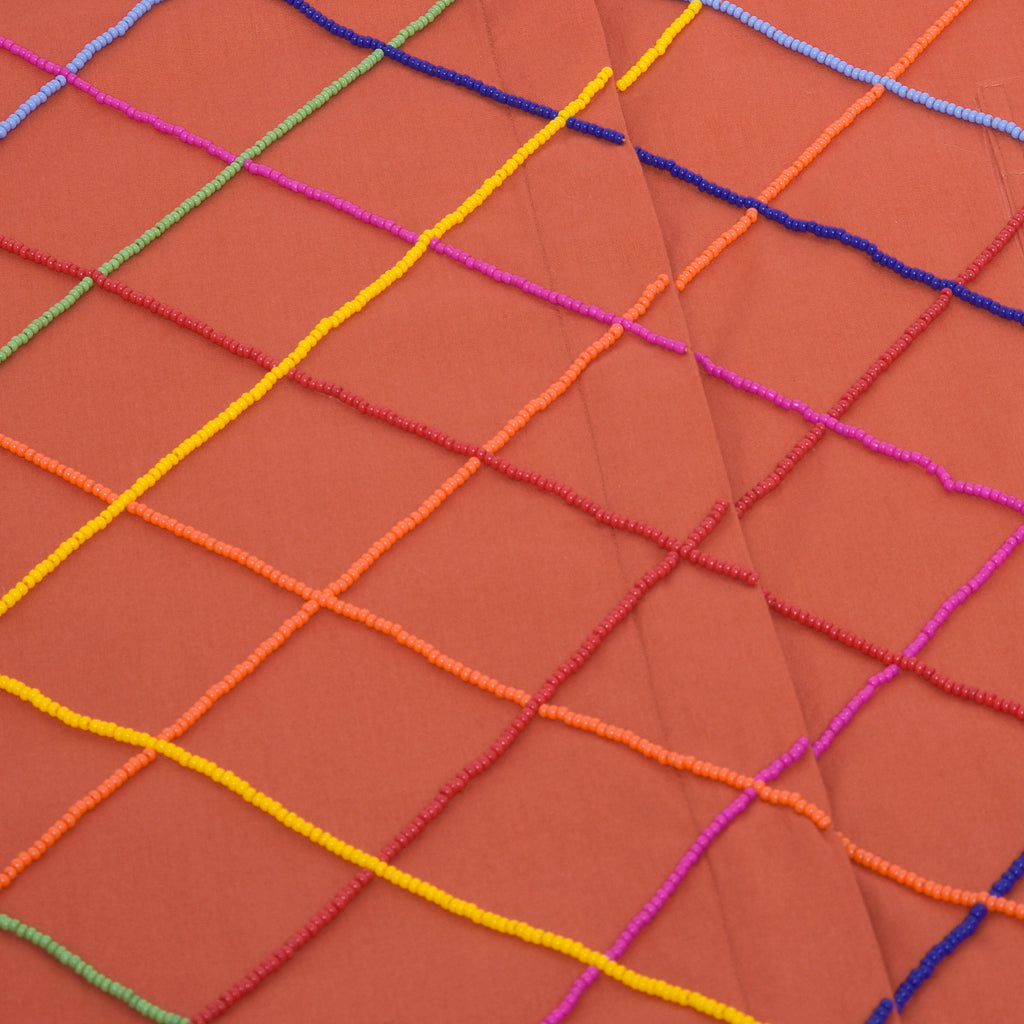 Close do bordado colorido artesanal na Camisa Vera Listras laranja feita em tricoline de algodão.