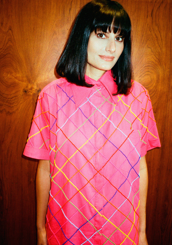 Modelo vestindo a Camisa Vera Listras rosa em tricoline de algodão, vista de frente com bordado artesanal colorido.