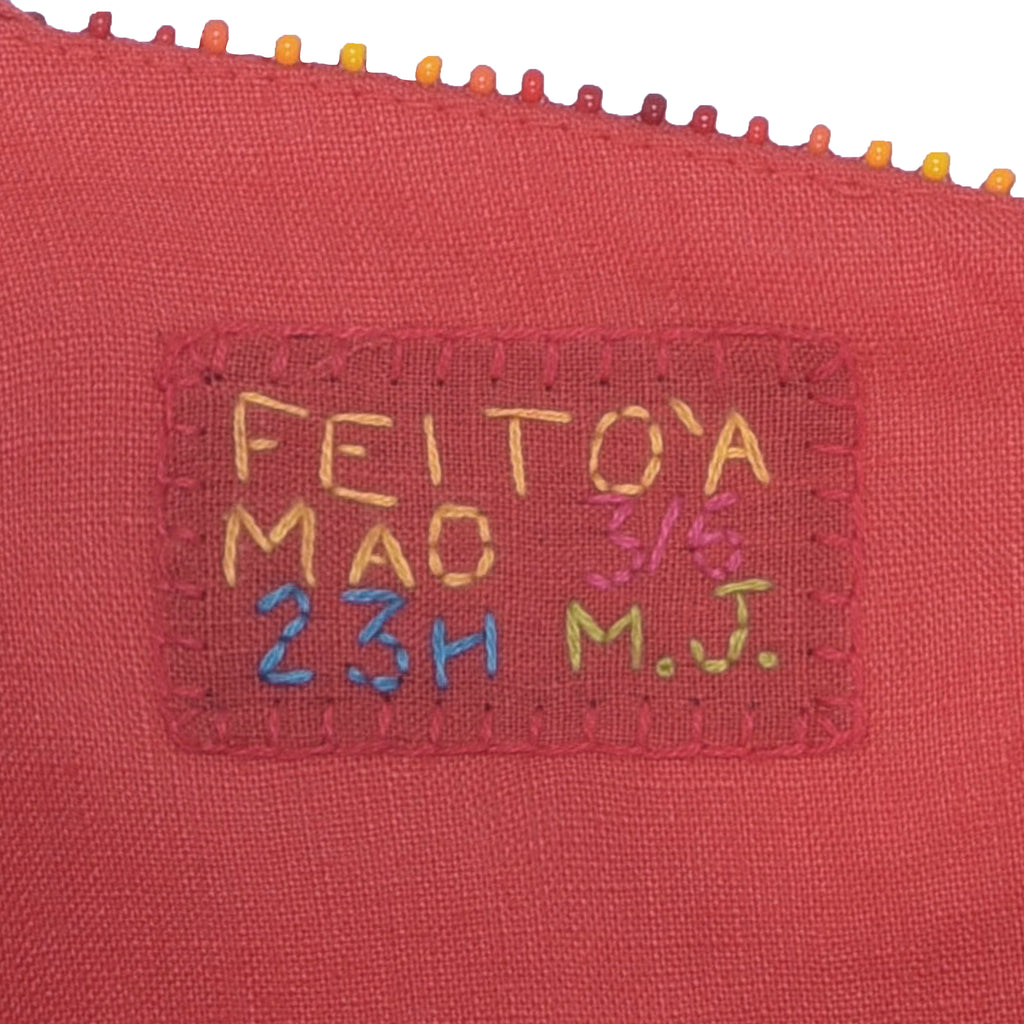 Etiqueta “Feito à Mão” bordada no vestido Betina Conchas, reforçando o caráter artesanal e exclusivo da peça.