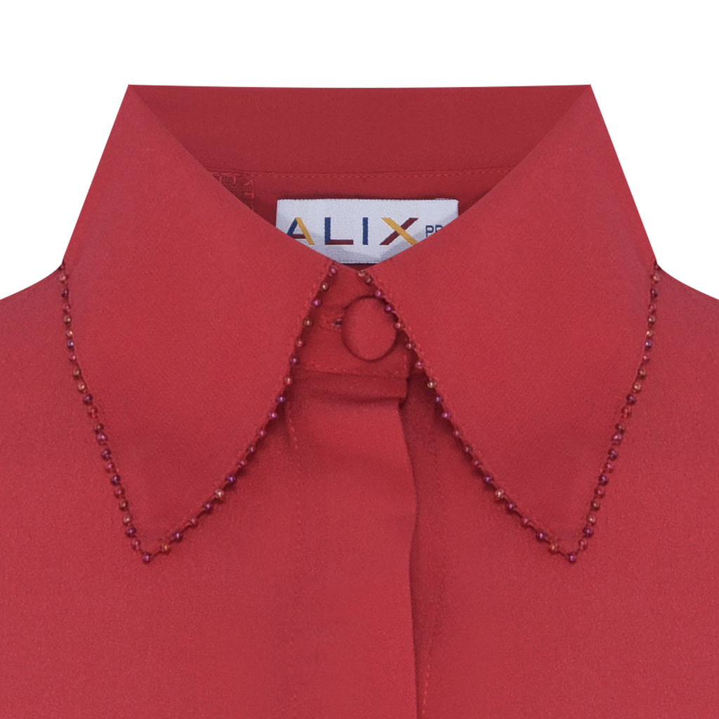 Detalhe da gola bordada à mão da Camisa Gala Vermelha com miçangas de vidro e costura artesanal.