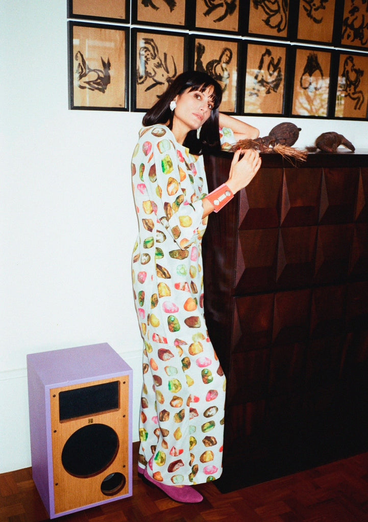 Modelo usando túnica Yas Pedraria lateralmente, combinada à calça do mesmo tecido chine due com estampa multicolorida.