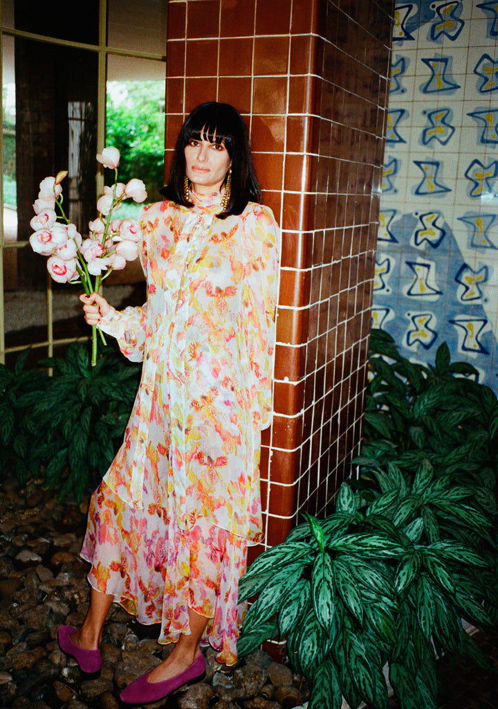 Modelo usando saia Chiffon Íris Violeta em seda com estampa floral multicolorida e caimento leve e sofisticado.