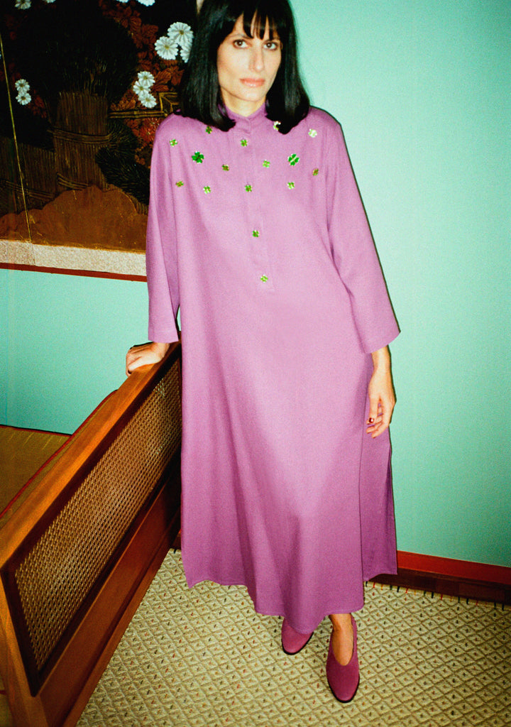 Modelo usando vestido Patricia Trevo roxo em linho misto com aviamentos verdes esmaltados e caimento longo e fluido.