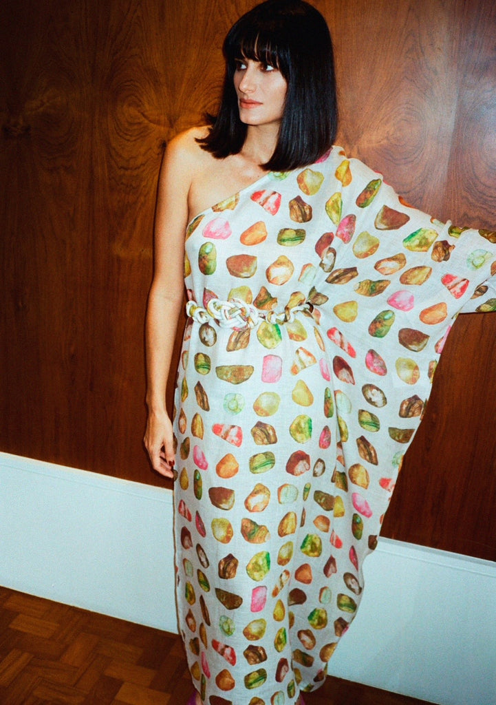 Modelo usando vestido Rafaela Pedraria de um ombro só em organza de linho com estampa aquarelada multicolorida e cinto trançado.