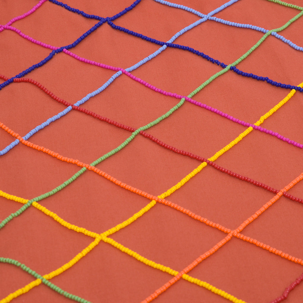 Detalhe do bordado manual em miçangas coloridas na saia Vera Listras laranja, feita em tricoline de algodão.