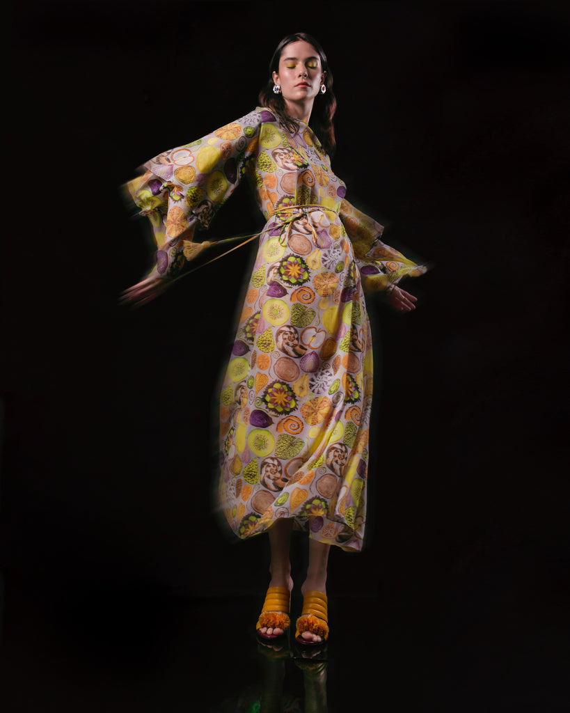 Modelo usando o Vestido 'Eva' Sagrada Geometria da Alix. Vestido feminino amplo em seda com estampa colorida e mangas longas.

