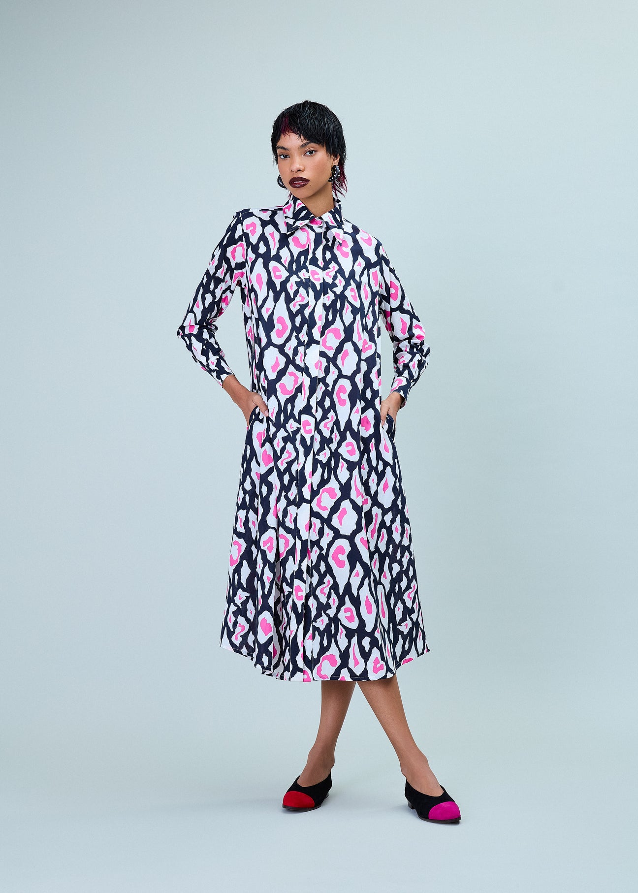 Modelo vestindo o Vestido ‘Milus’ Onça com estampa de onça em preto, rosa e branco, confeccionado em algodão exportação com pati invisível e bolsos laterais.